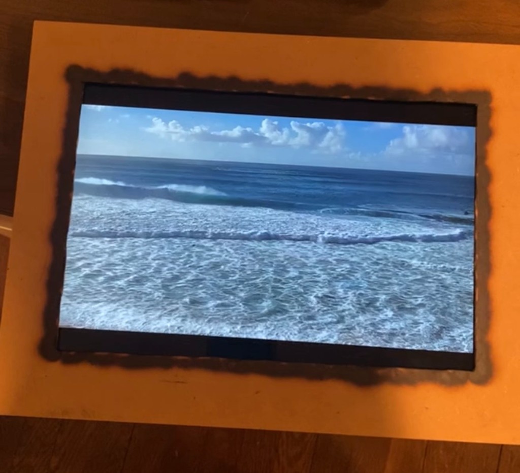 Early DIY LiveFrame prototype — a tablet in a janky wooden picture frame showing a live beach cam